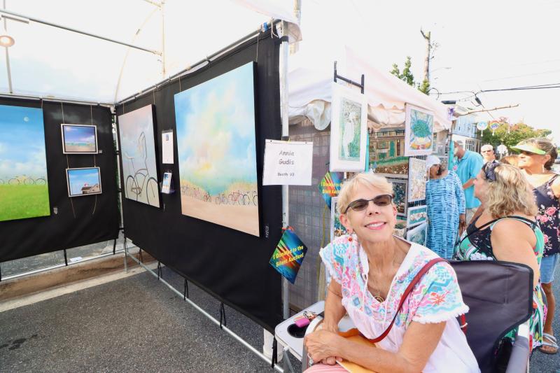 Annie Gudis sits in front of her original oil paintings of bicycles at the beach. She said she is inspired by the view from her studio in North Shores. It was Gudis’ first year doing the art show.